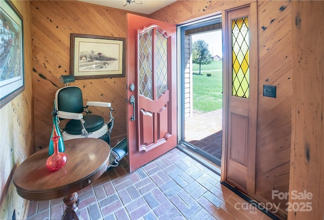entryway with wooden walls and brick floor