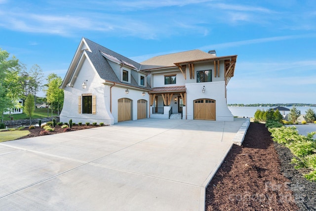 view of front facade featuring a standing seam roof, an attached garage, concrete driveway, and a porch