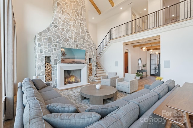 living room with beamed ceiling, high vaulted ceiling, wood finished floors, and a fireplace