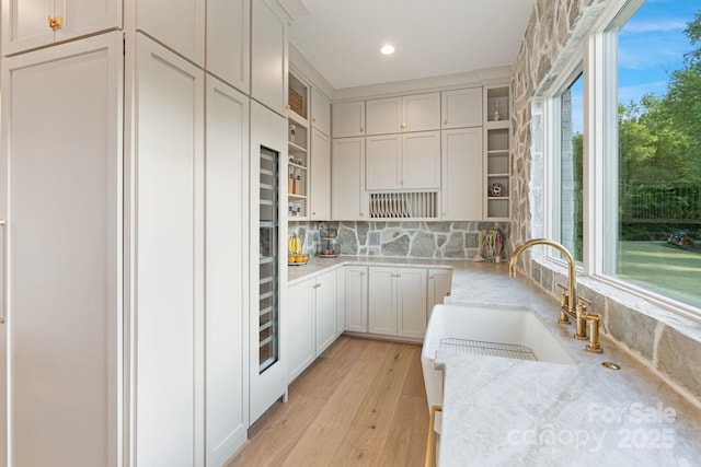 kitchen with open shelves, light stone countertops, recessed lighting, light wood finished floors, and backsplash