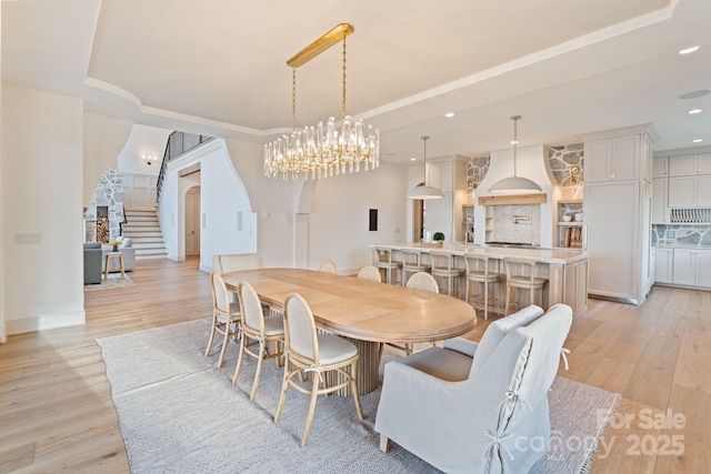 dining area featuring recessed lighting, light wood-style flooring, stairs, and a tray ceiling