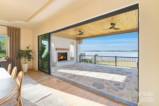 interior space with a water view, wood finished floors, and an outdoor brick fireplace
