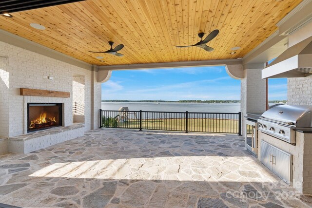 view of patio with a water view, ceiling fan, an outdoor brick fireplace, an outdoor kitchen, and a grill