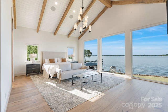 bedroom with beam ceiling, high vaulted ceiling, a chandelier, hardwood / wood-style floors, and a water view