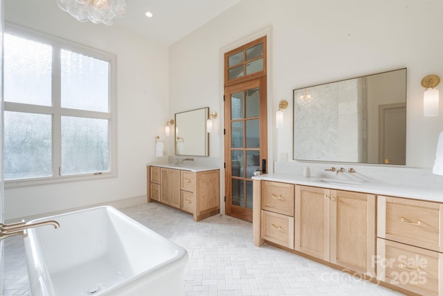 full bathroom with a sink, a soaking tub, and two vanities
