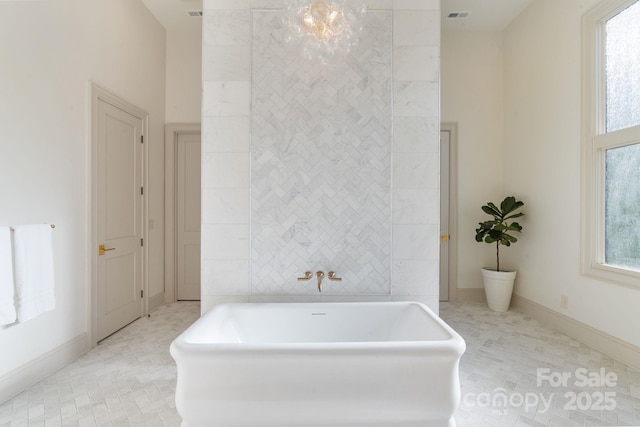 bathroom with visible vents, baseboards, a wealth of natural light, and a soaking tub