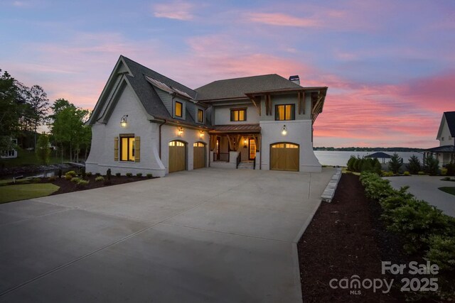 view of front of property with a garage, covered porch, a chimney, and concrete driveway
