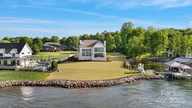 exterior space featuring boat lift, an outdoor pool, a water view, a chimney, and a lawn