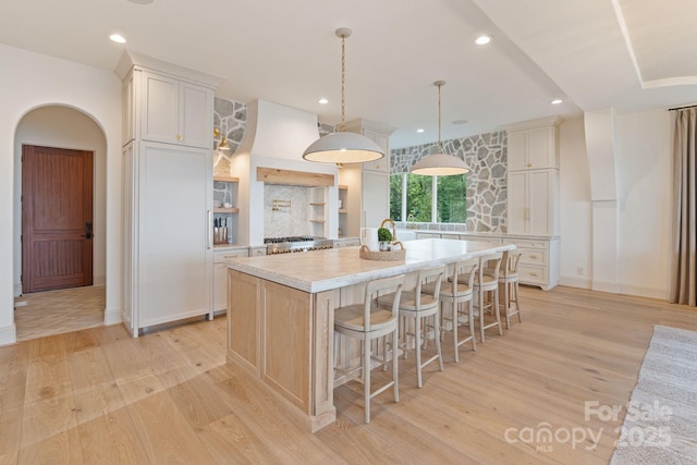 7679 Rabbit Cir, Denver, NC 28037 - kitchen featuring light countertops, a center island, light wood finished floors, a kitchen bar, and white cabinetry