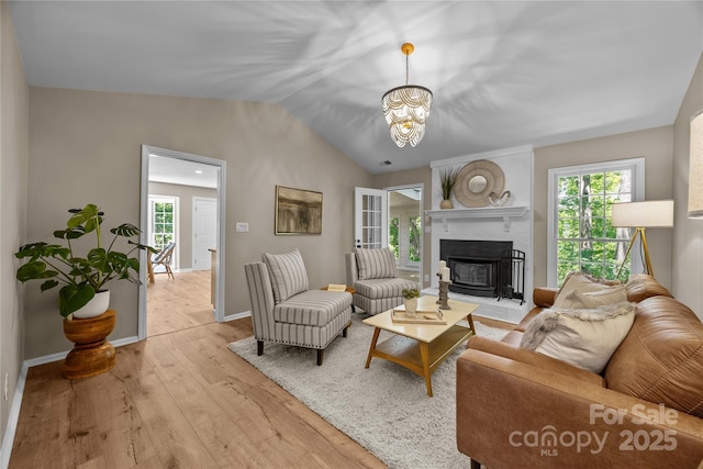 living room with light wood-type flooring, a chandelier, plenty of natural light, baseboards, and vaulted ceiling