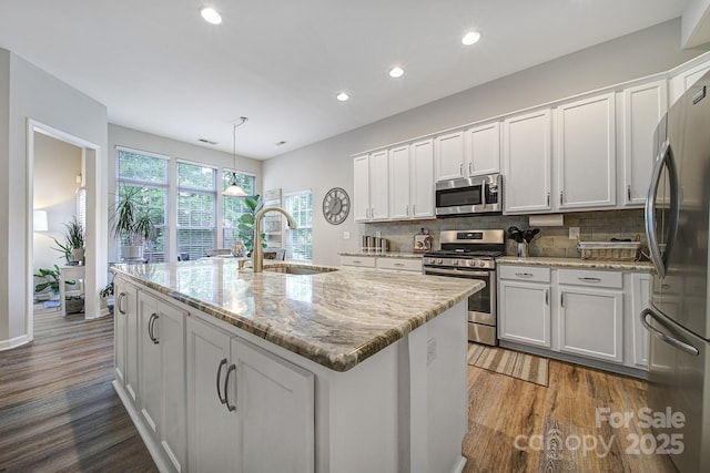 7123 Meyer Rd, Fort Mill, SC 29715 - kitchen featuring white cabinets, a kitchen island with sink, a sink, wood finished floors, and appliances with stainless steel finishes