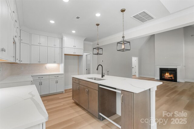 925 Twin Lakes Rd, Rock Hill, SC 29732 - kitchen with a sink, light wood-type flooring, a kitchen island with sink, light stone counters, and crown molding