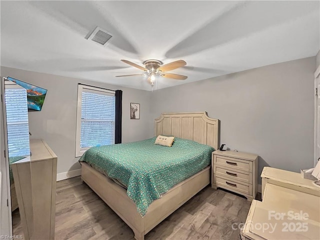 bedroom with baseboards, a ceiling fan, wood finished floors, and visible vents
