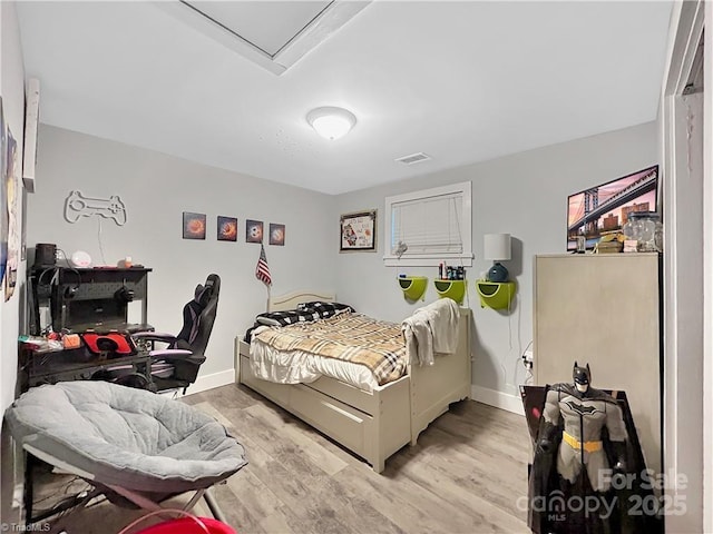 bedroom featuring light wood-style flooring, visible vents, and baseboards