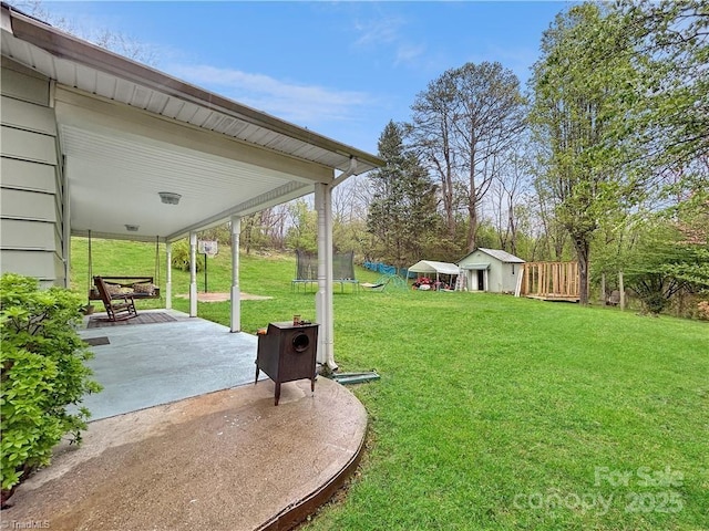 view of yard featuring a shed, an outdoor structure, a patio, and a trampoline