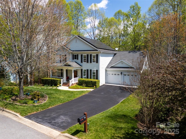 view of front of home with aphalt driveway, solar panels, covered porch, a front yard, and a garage