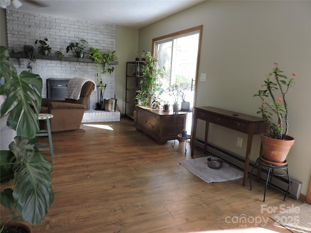 living area with baseboard heating, wood finished floors, and a fireplace