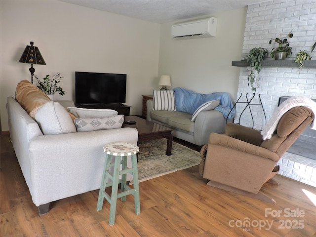 living area with wood finished floors, a fireplace, and a wall mounted air conditioner
