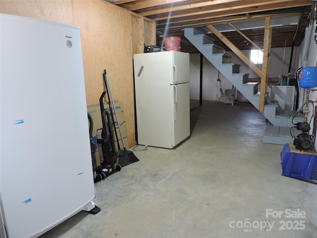unfinished below grade area featuring freestanding refrigerator and stairs