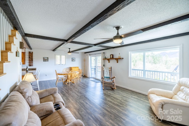 living area featuring a textured ceiling, baseboards, beamed ceiling, wood finished floors, and ceiling fan