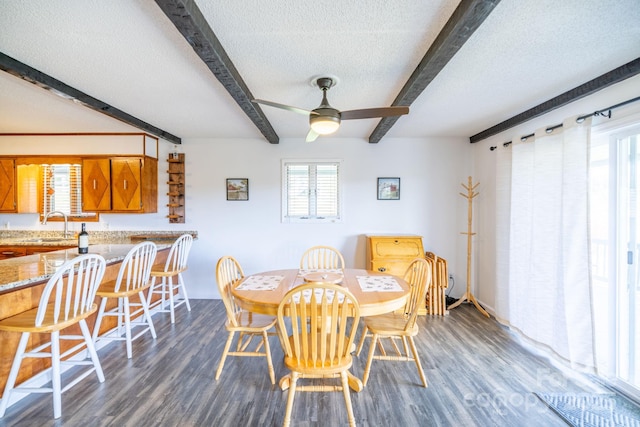dining space featuring a textured ceiling, beam ceiling, a ceiling fan, and dark wood-style flooring
