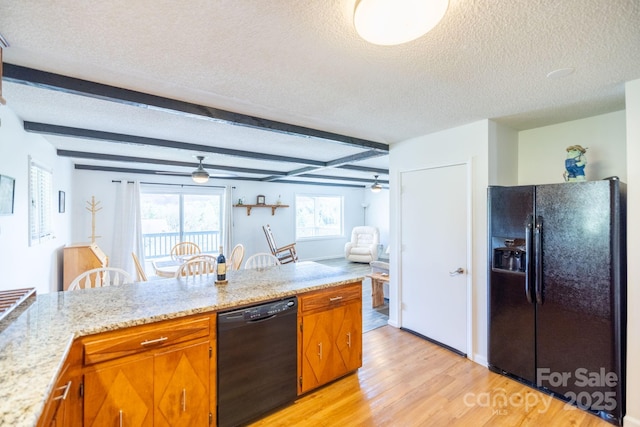 kitchen with brown cabinets, light wood-style flooring, a textured ceiling, and black appliances