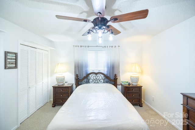 bedroom with light colored carpet, ceiling fan, baseboards, and a closet