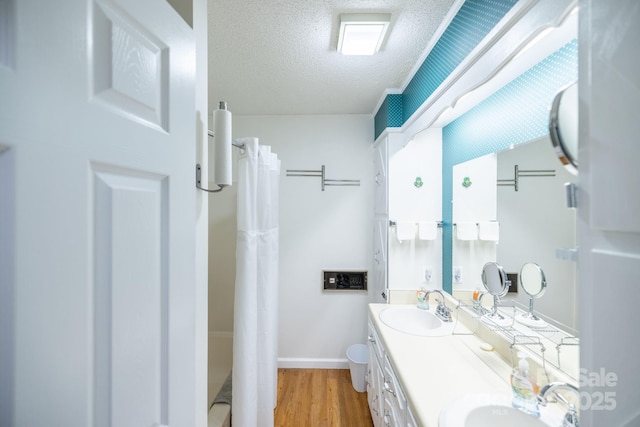 bathroom featuring wood finished floors, a sink, a textured ceiling, and double vanity