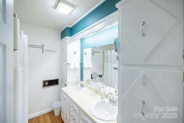 full bathroom featuring wood finished floors, a sink, a textured ceiling, and double vanity