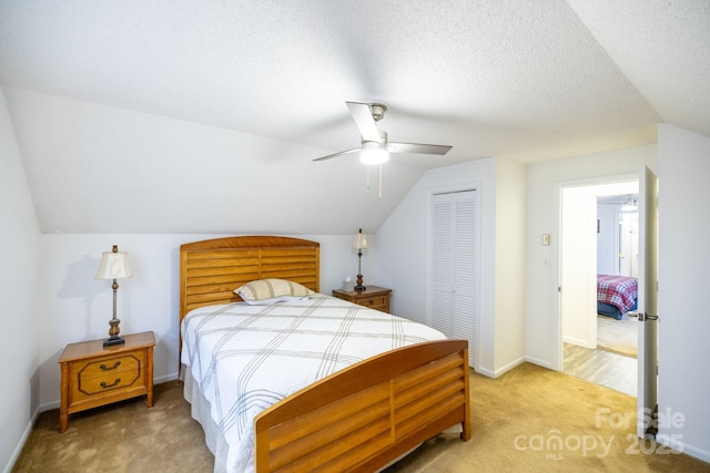 bedroom with a ceiling fan, a closet, light colored carpet, baseboards, and lofted ceiling