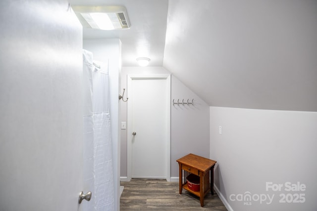 hall with lofted ceiling, baseboards, wood finished floors, and visible vents