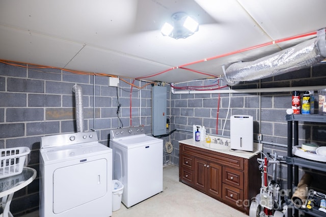 laundry room with laundry area, concrete block wall, a sink, washing machine and dryer, and electric panel