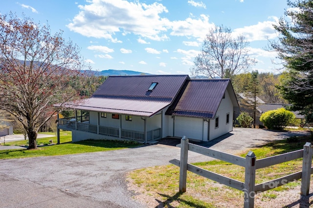 view of front of house with a porch, metal roof, fence, a garage, and aphalt driveway