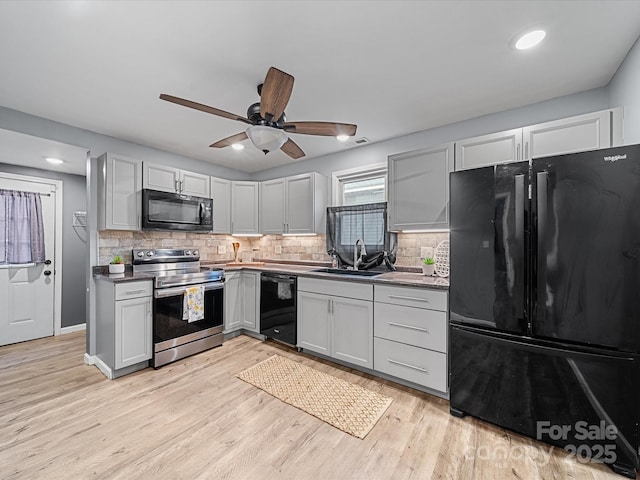 kitchen featuring black appliances, a sink, decorative backsplash, light wood-style floors, and recessed lighting