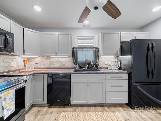 kitchen featuring a sink, black appliances, ceiling fan, backsplash, and light wood finished floors