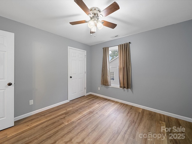 spare room featuring baseboards, wood finished floors, and ceiling fan