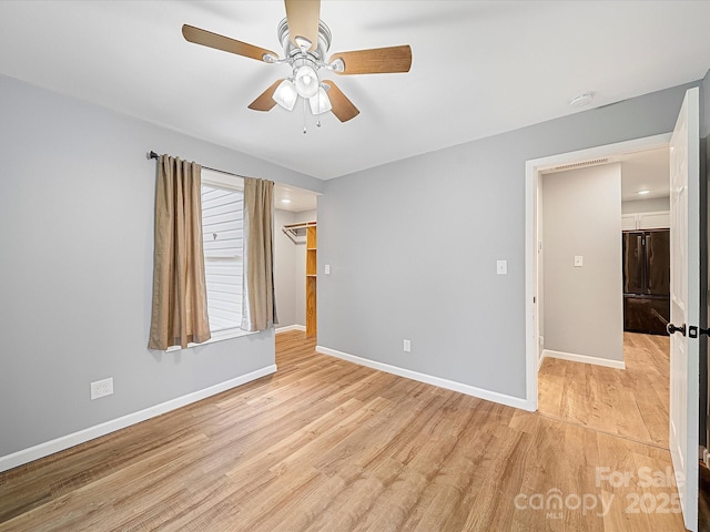 empty room with baseboards, light wood finished floors, ceiling fan, and a smoke detector