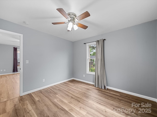 spare room featuring light wood-style floors, a smoke detector, ceiling fan, and baseboards