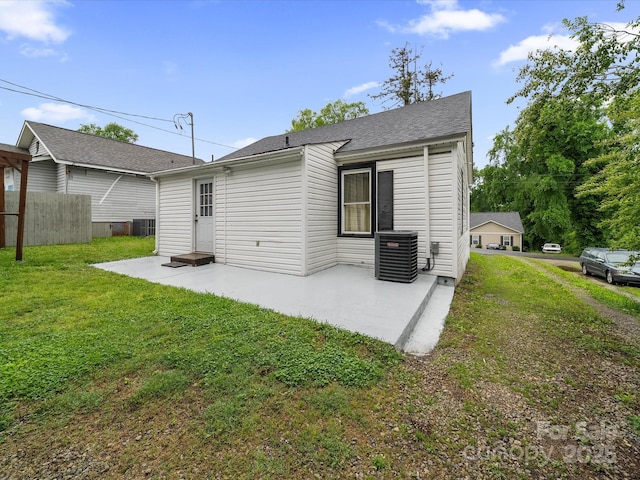 rear view of house with central AC unit, a patio area, and roof with shingles