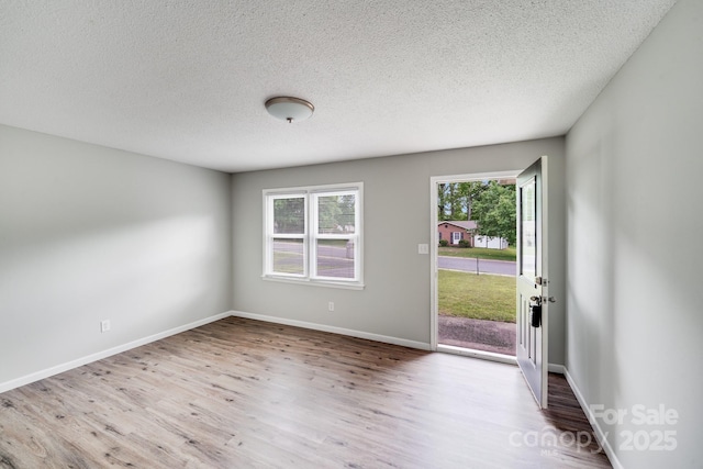 empty room with baseboards, wood finished floors, and a textured ceiling