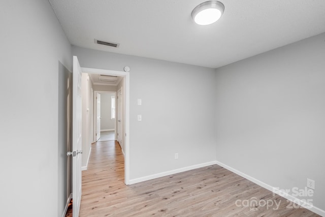 empty room featuring light wood-style flooring, visible vents, and baseboards