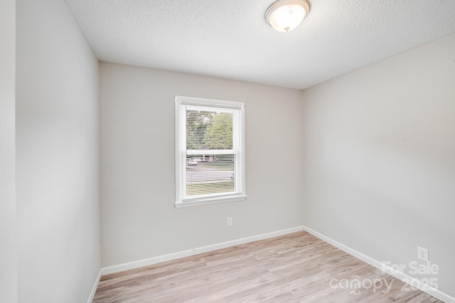 unfurnished room with baseboards, a textured ceiling, and light wood-style floors