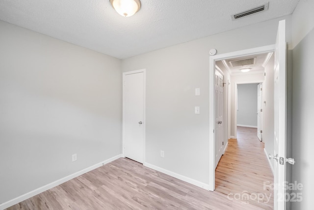 spare room with visible vents, light wood finished floors, and baseboards