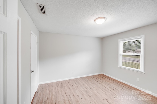 unfurnished room with baseboards, visible vents, a textured ceiling, and light wood finished floors