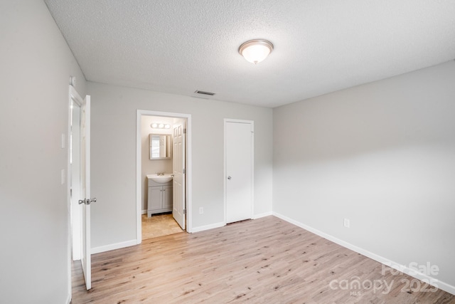 unfurnished bedroom with light wood-type flooring, baseboards, visible vents, and a textured ceiling