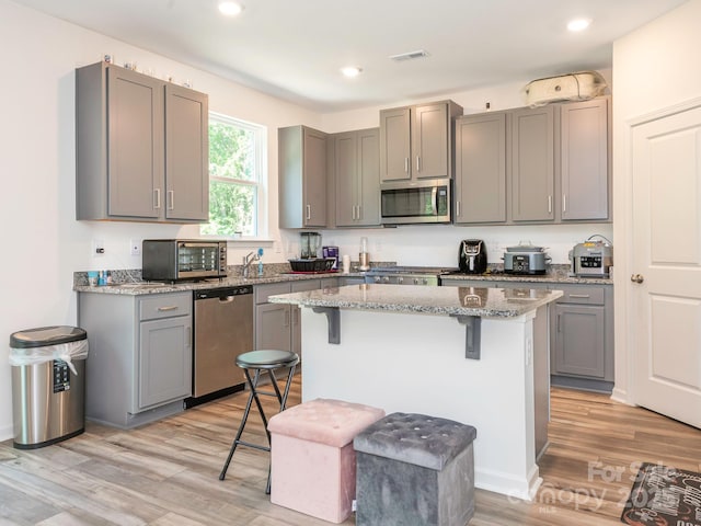 11010 Redcoat Hill Ln, Huntersville, NC 28078 - kitchen featuring appliances with stainless steel finishes, a breakfast bar, gray cabinetry, light stone countertops, and recessed lighting
