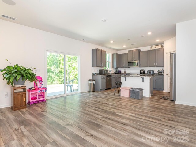 11010 Redcoat Hill Ln, Huntersville, NC 28078 - kitchen with stainless steel appliances, gray cabinets, a kitchen breakfast bar, a center island, and light wood finished floors