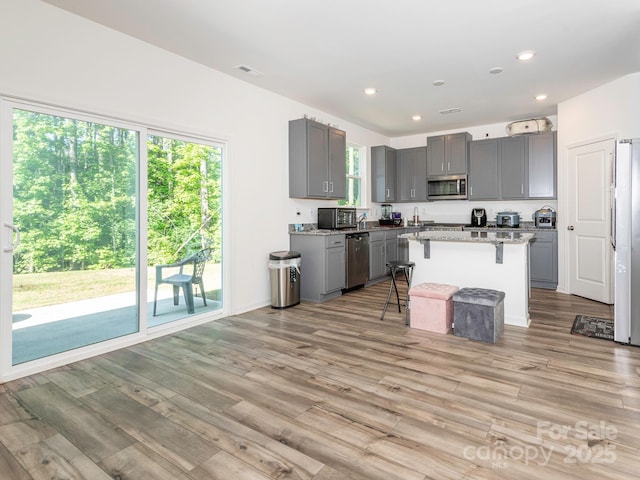 11010 Redcoat Hill Ln, Huntersville, NC 28078 - kitchen with appliances with stainless steel finishes, gray cabinetry, a breakfast bar area, light wood-style flooring, and recessed lighting