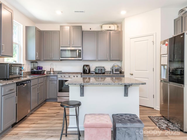 11010 Redcoat Hill Ln, Huntersville, NC 28078 - kitchen with appliances with stainless steel finishes, gray cabinetry, a breakfast bar, light wood-style flooring, and recessed lighting