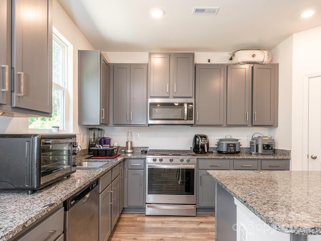 11010 Redcoat Hill Ln, Huntersville, NC 28078 - kitchen with stainless steel appliances, gray cabinets, a sink, light wood finished floors, and light stone counters